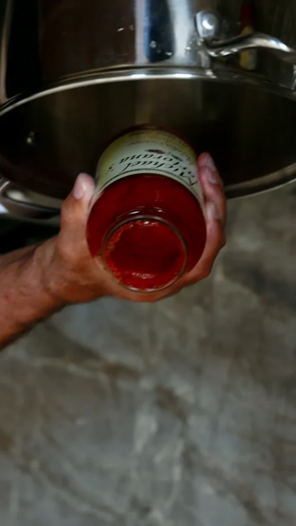 Pouring a jar of Michael's Sicilian sauce into the pot