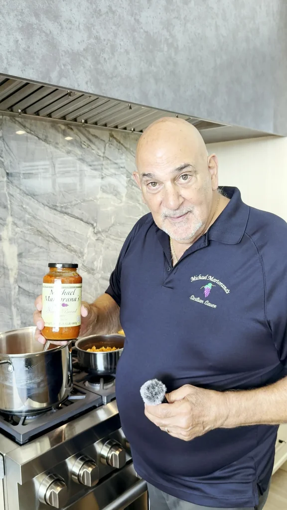 Michael Martorana at his stove holding a jar of his Sicilian sauce
